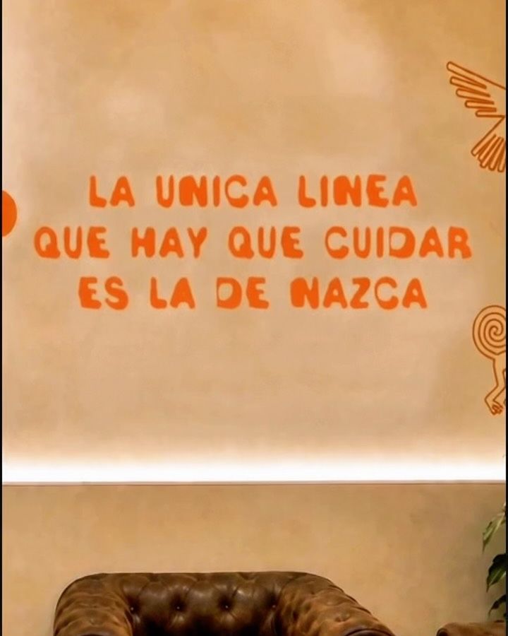 Pared del local con la frase «La única línea que hay que cuidar es la de Nazca» y un sillón Chester