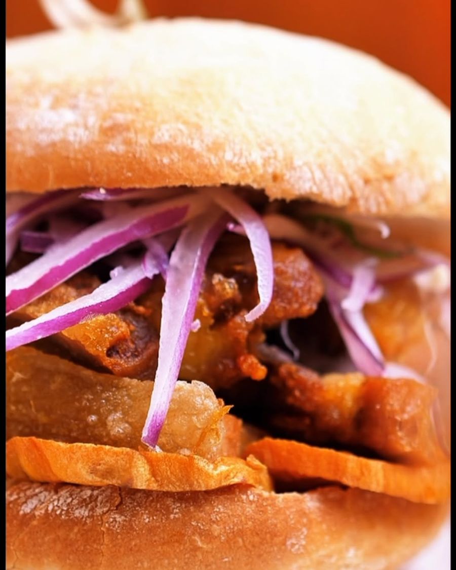 Sánguche de chicharrón con boniato y cebolla morada en pan crujiente